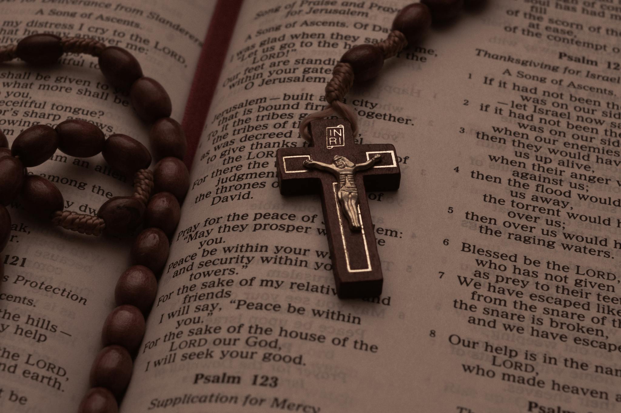 A rosary beads and crucifix resting on an open Bible displaying Psalms.