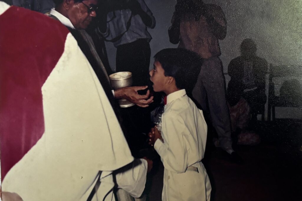 A young Catholic boy receiving the Holy Eucharist from a priest during his First Communion